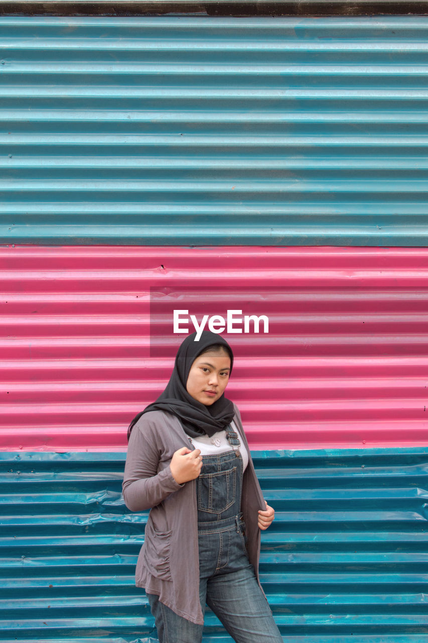 Portrait of girl standing against metal in city