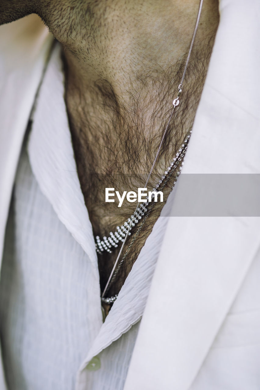Midsection of man wearing necklaces and chain