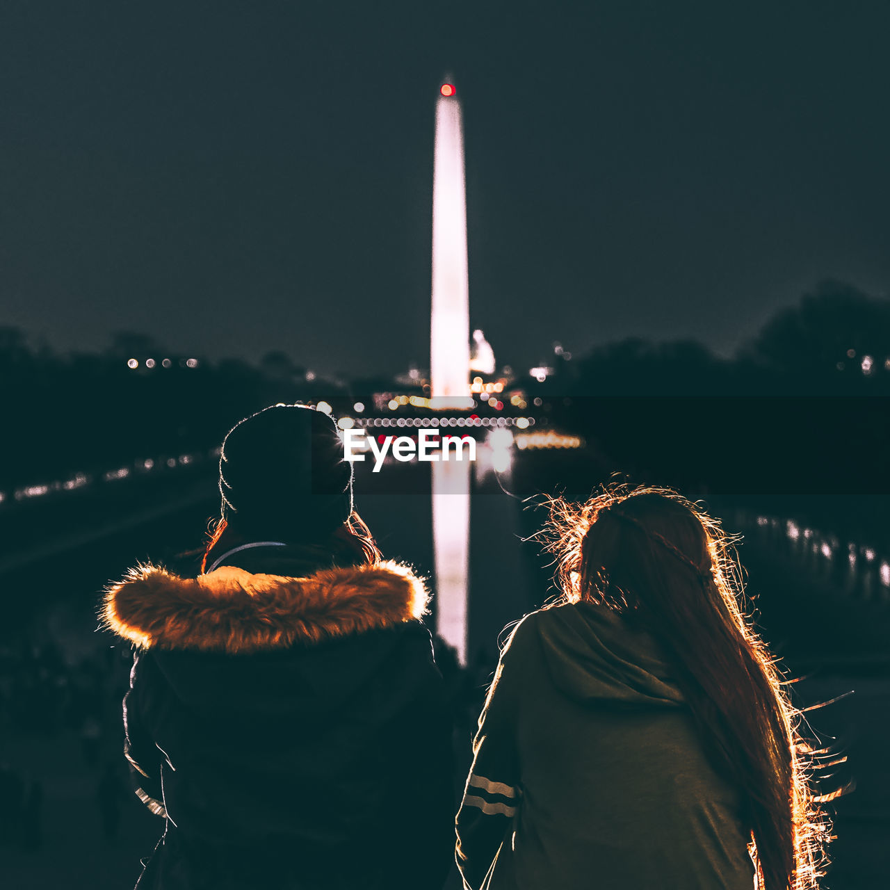 Rear view of female friends looking at illuminated washington monument at night