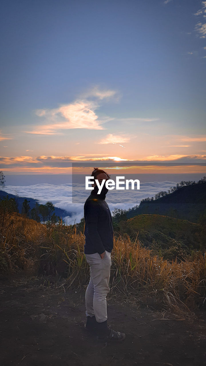 Man standing on field against sky during sunset