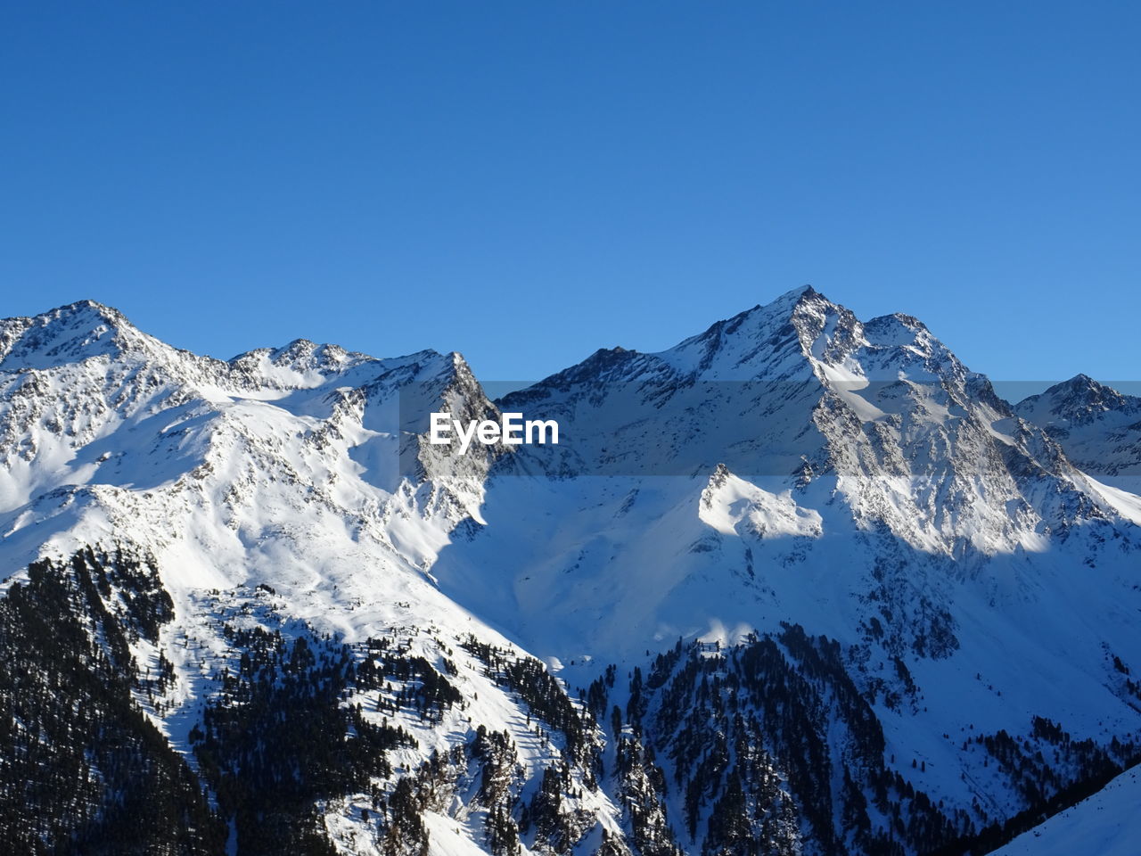 Scenic view of snowcapped mountains against clear blue sky