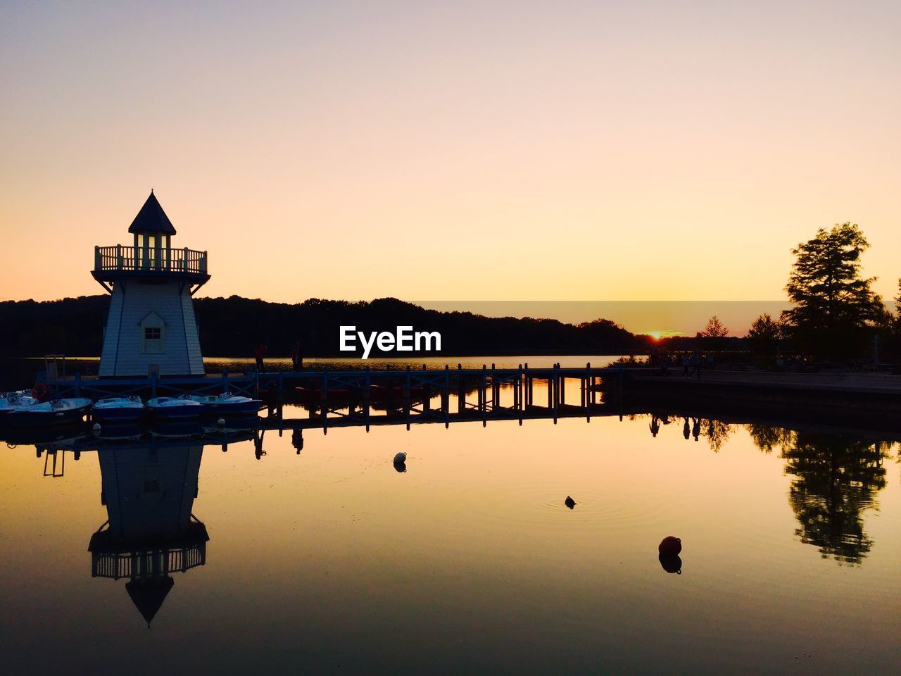 Lighthouse in lake during sunset