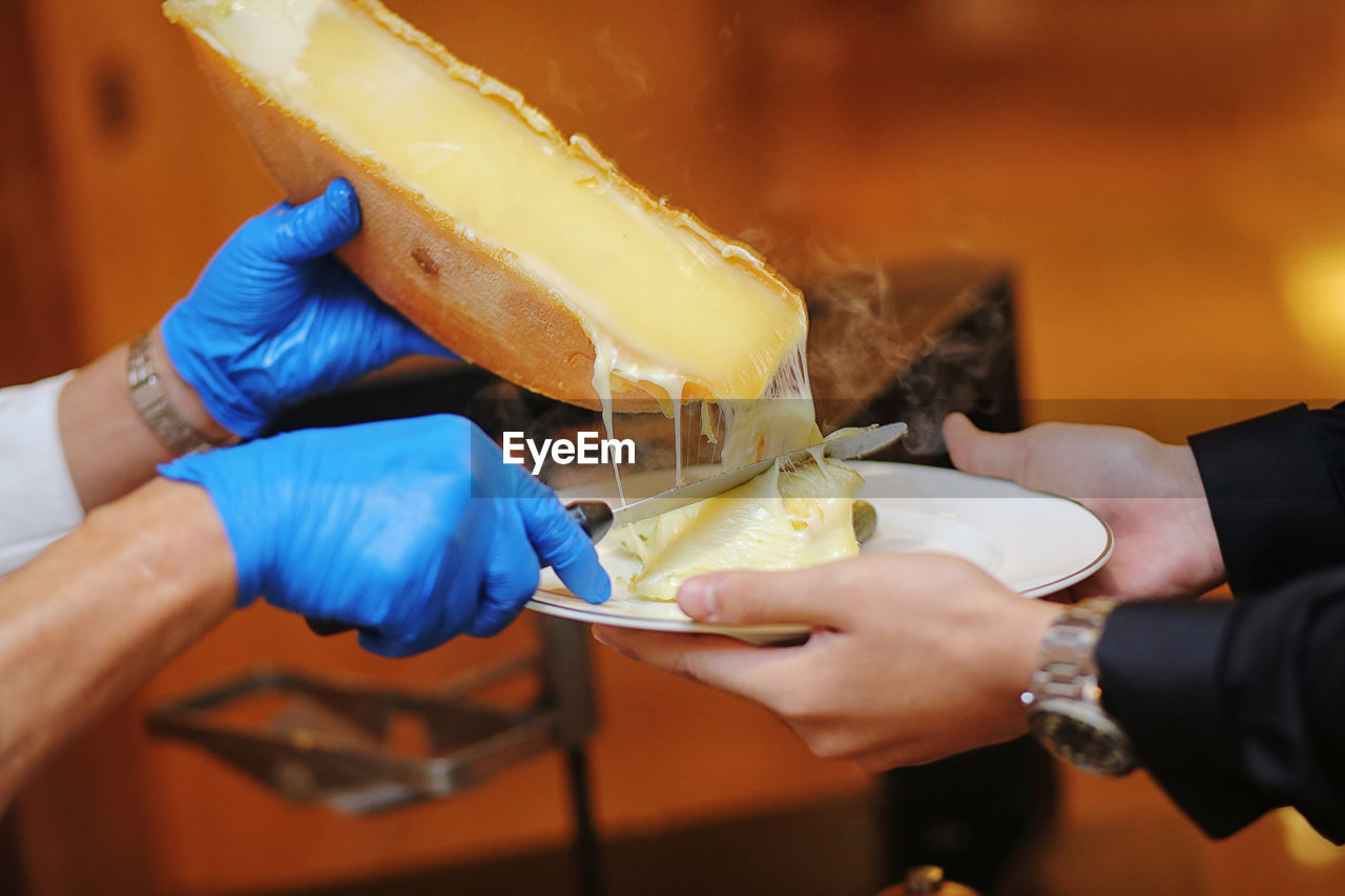 Cropped hands of cheesemonger serving cheese to customer in plate