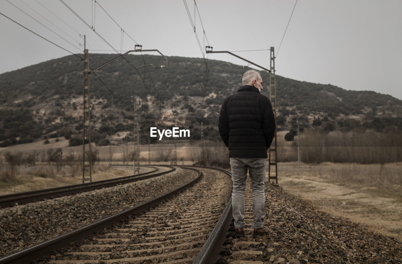 Adult man in warm clothing with railway in countryside. shot in castilla la mancha, spain