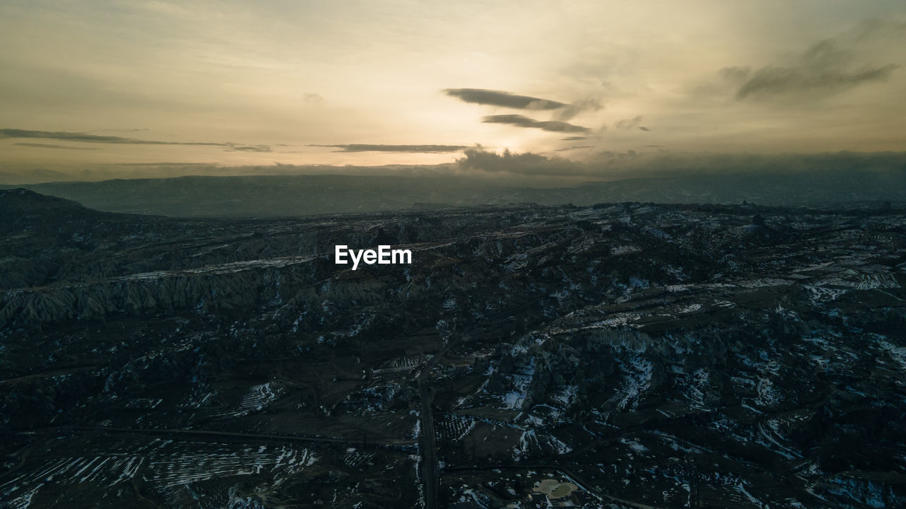 AERIAL VIEW OF SNOWCAPPED LANDSCAPE AGAINST SKY DURING SUNSET