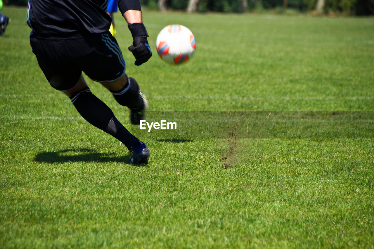 Low section of man playing soccer on field