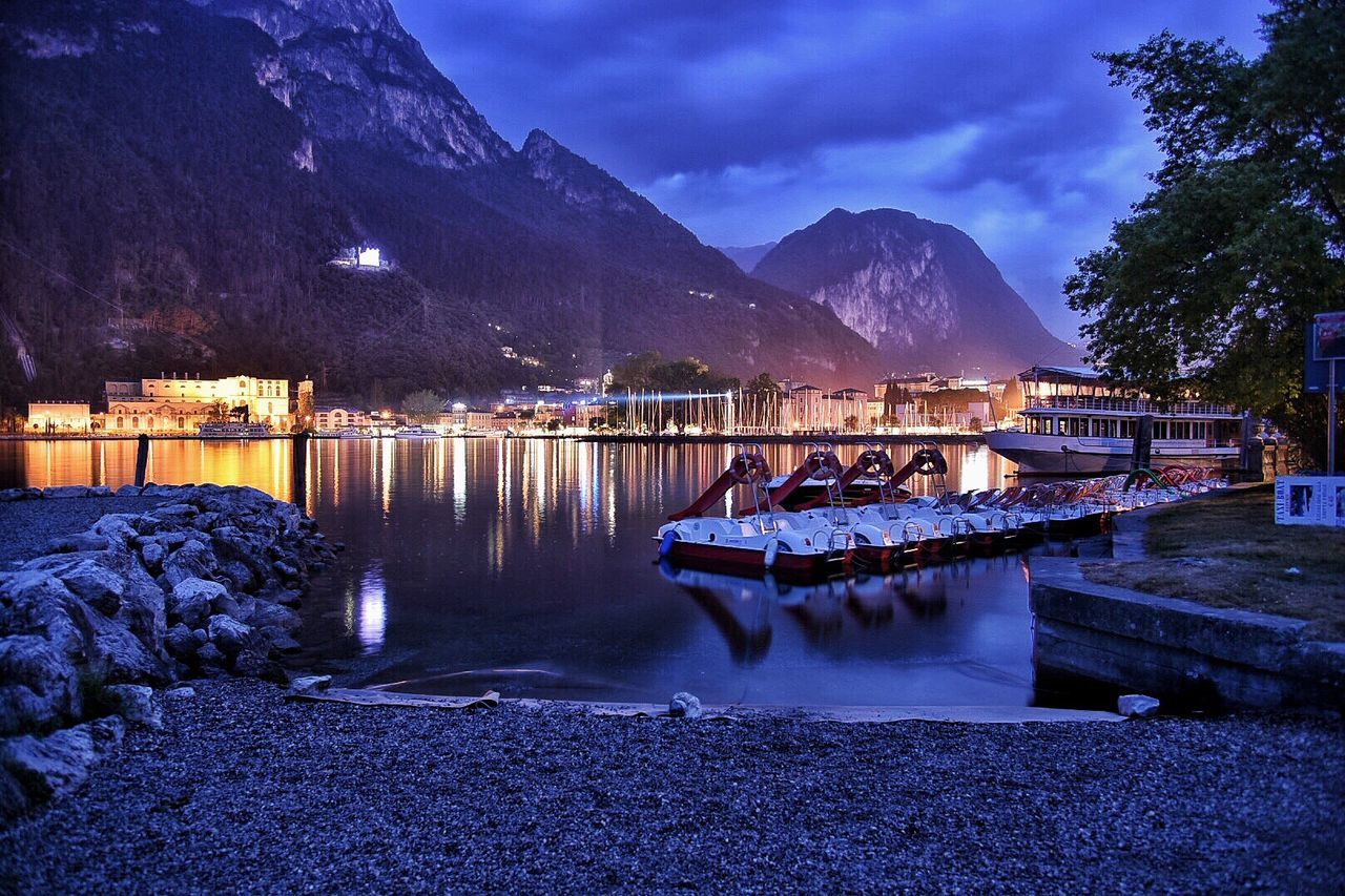 Boats moored at harbor against sky at night