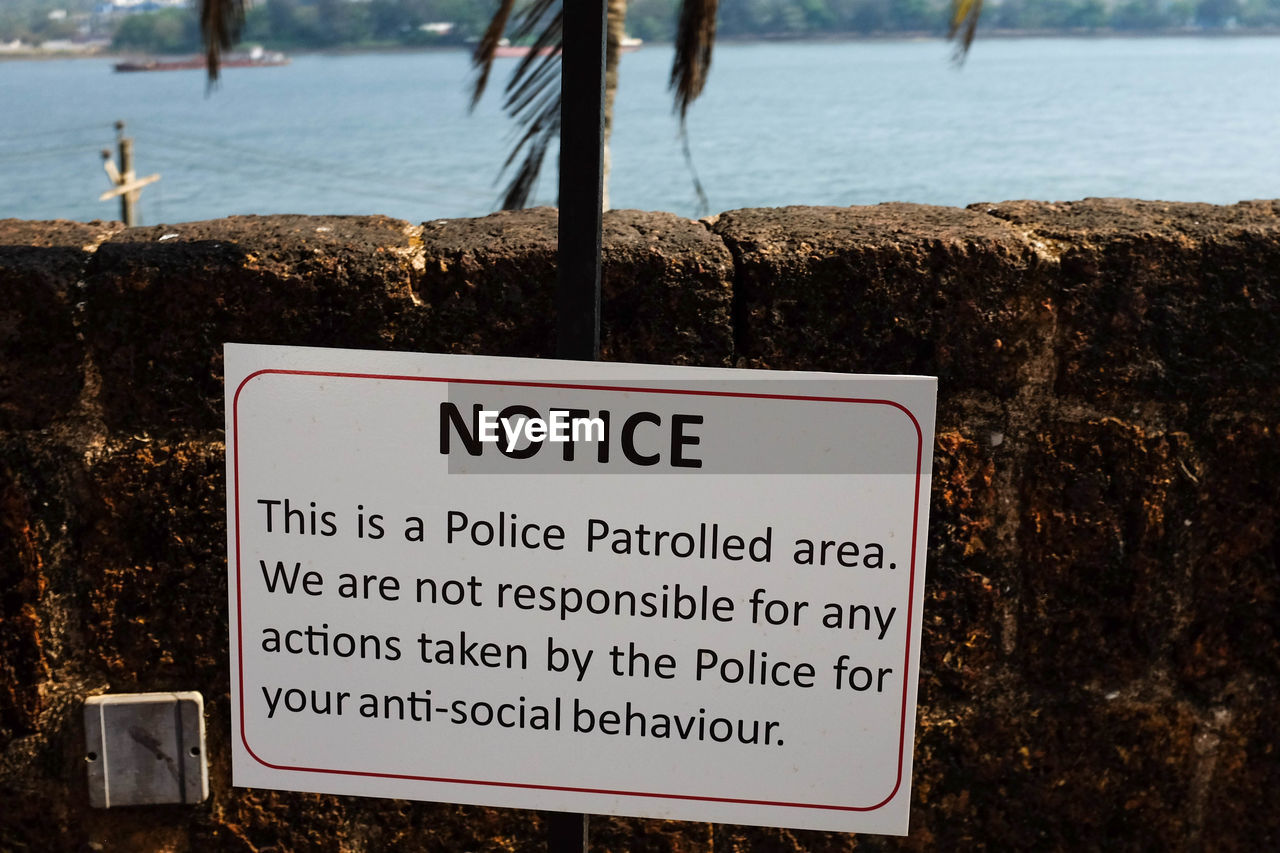 CLOSE-UP OF SIGNBOARD AGAINST CALM SEA