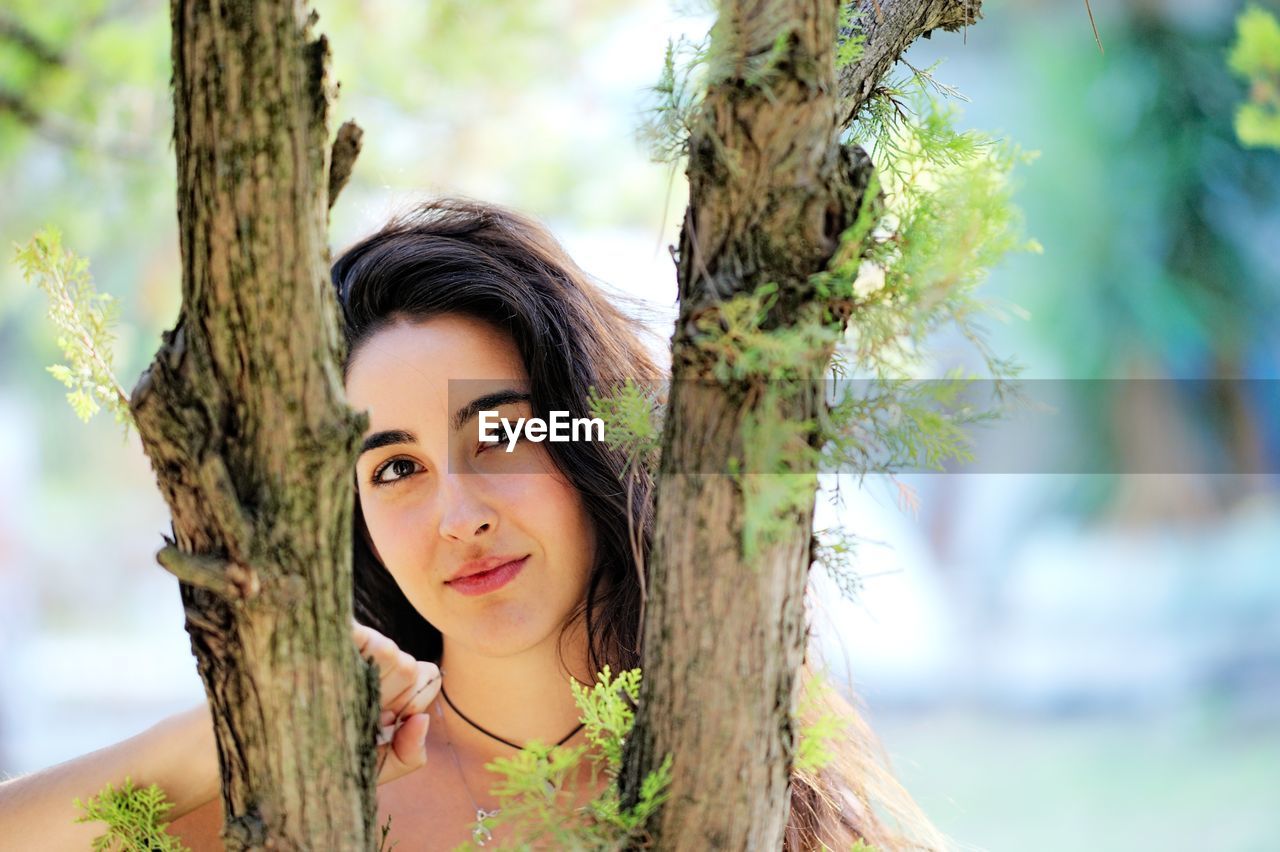 Portrait of young woman seen through branches
