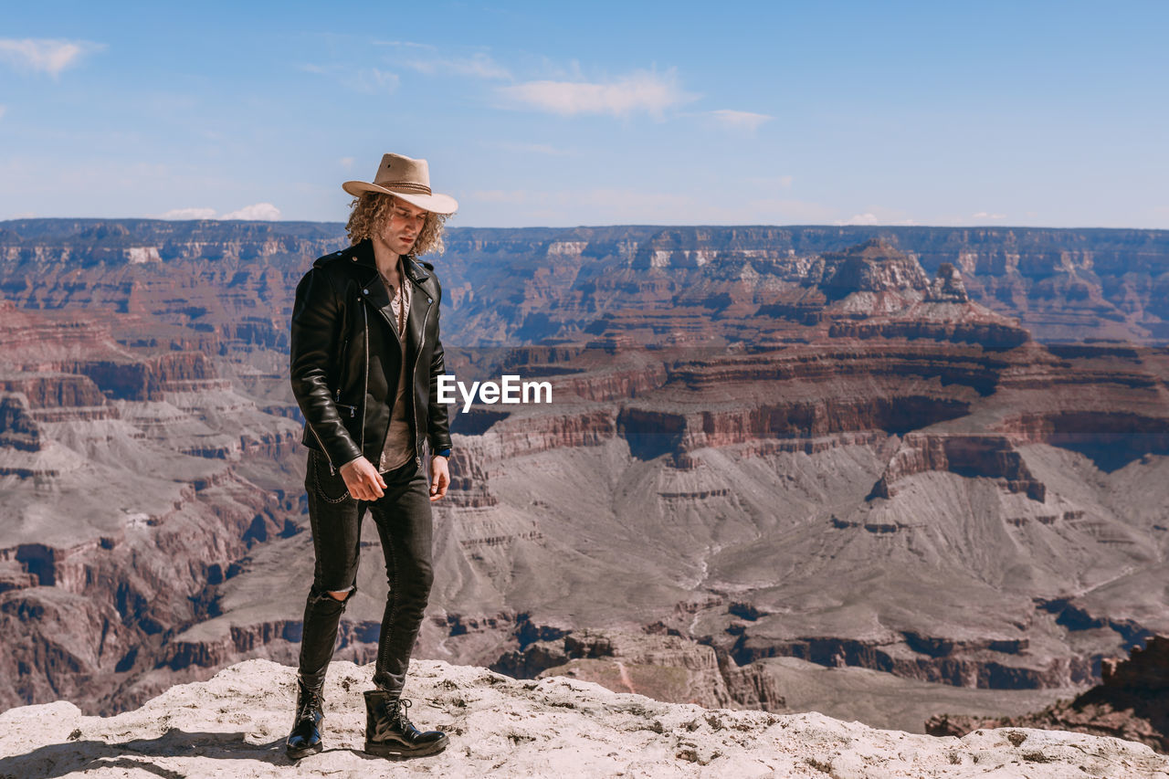 FULL LENGTH OF MAN STANDING ON ROCK AGAINST SKY