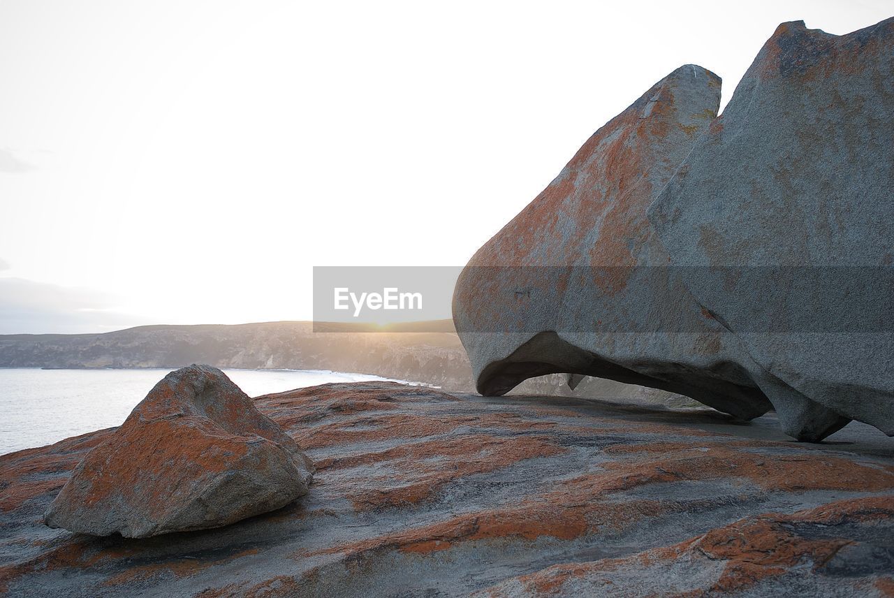 Rock formation in sea against clear sky