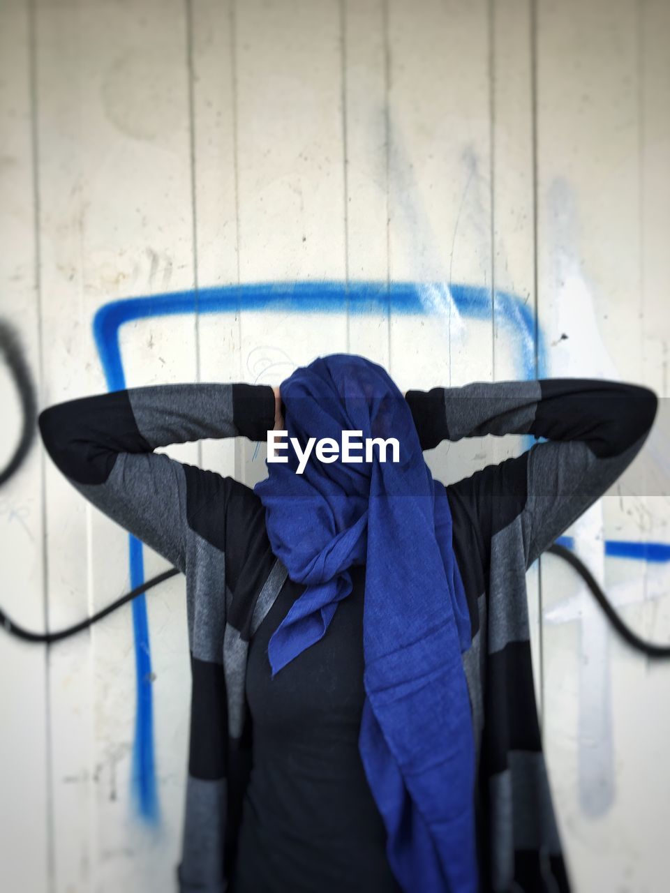 Woman with obscured face standing against wall