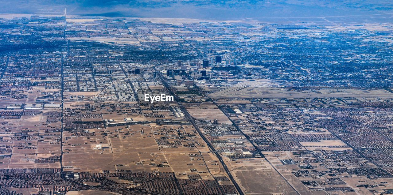 HIGH ANGLE VIEW OF CITYSCAPE AND AIRPLANE AGAINST SKY