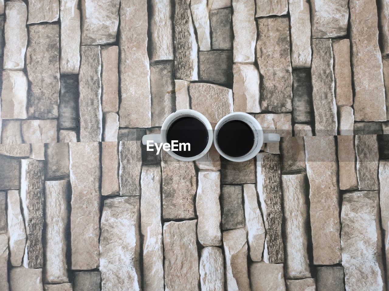 DIRECTLY ABOVE SHOT OF COFFEE CUPS AGAINST WALL