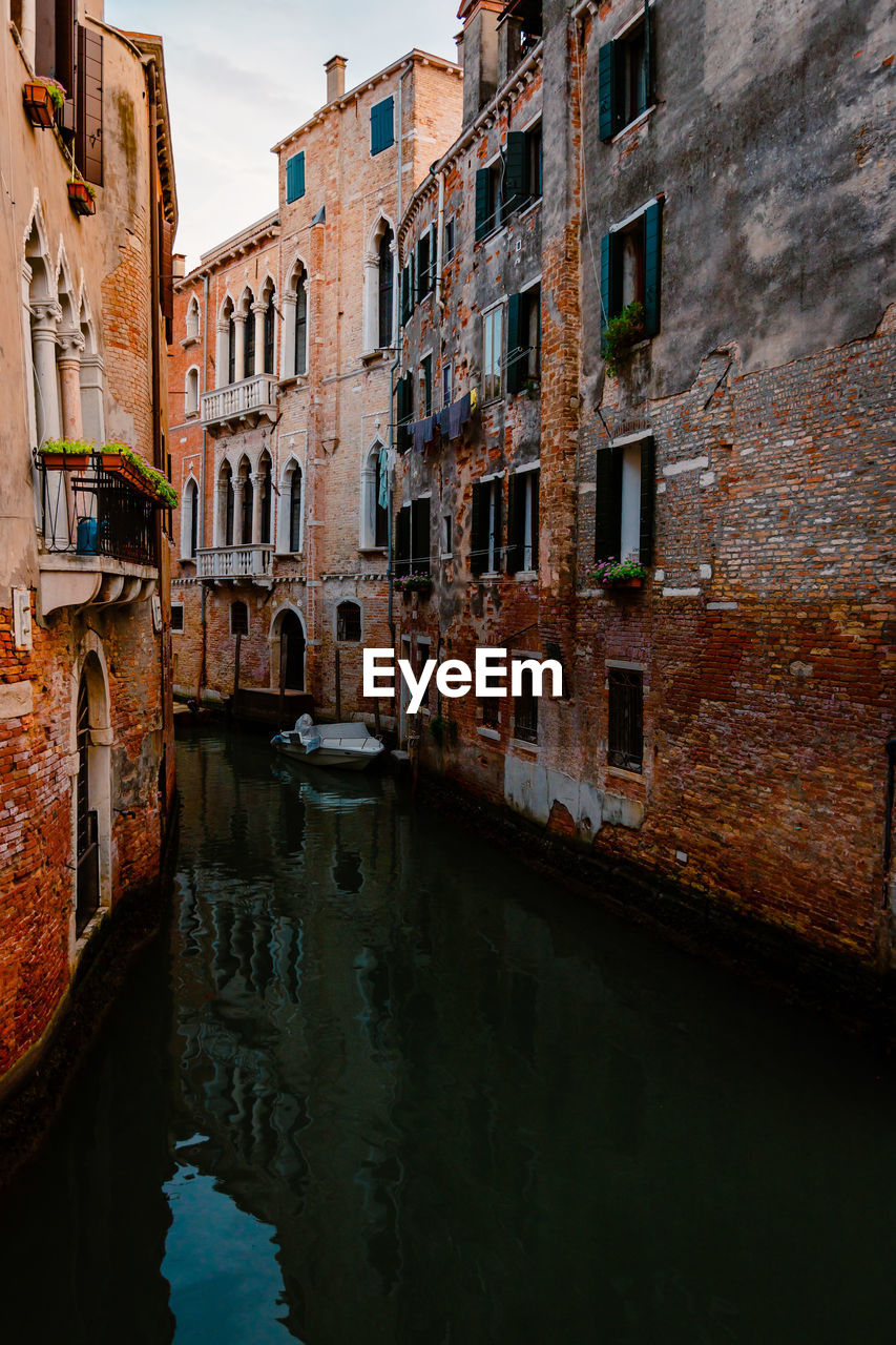 Venetian foreshortening with typical canal and boat moored under houses