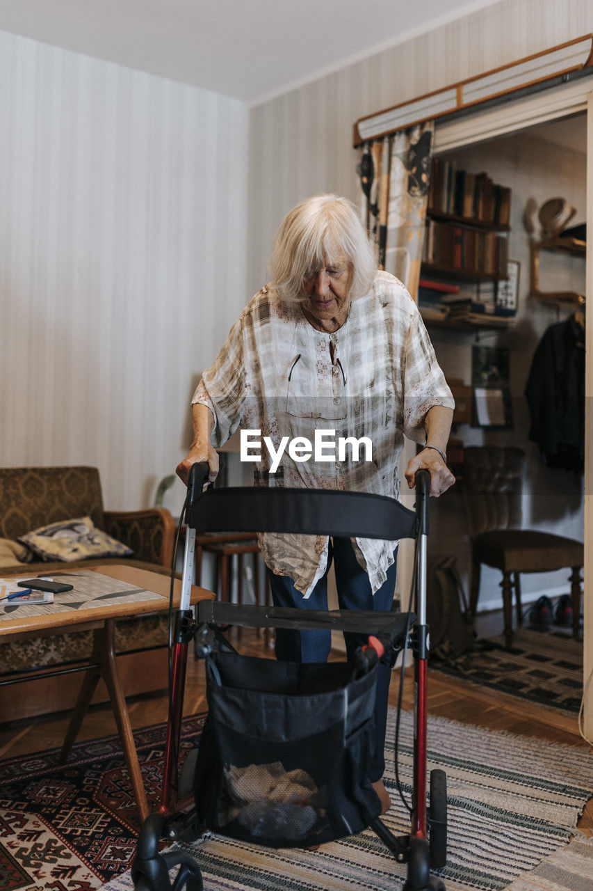 Senior woman walking at home using mobility walker