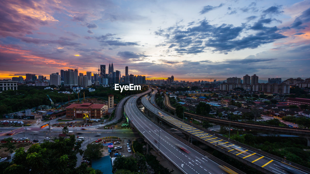 High angle view of street amidst buildings against sky during sunset