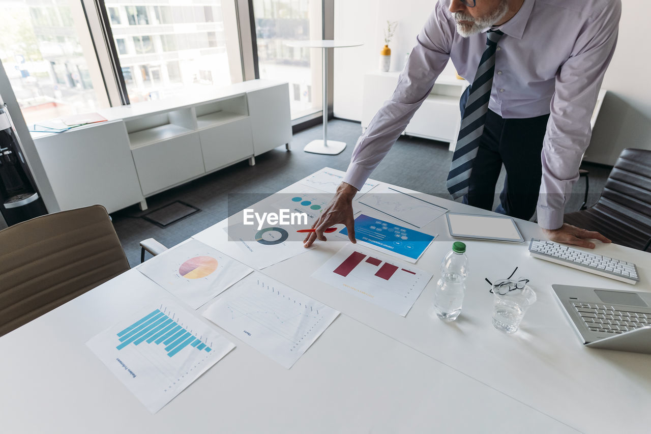 Businessman examining charts and graphs at desk in office