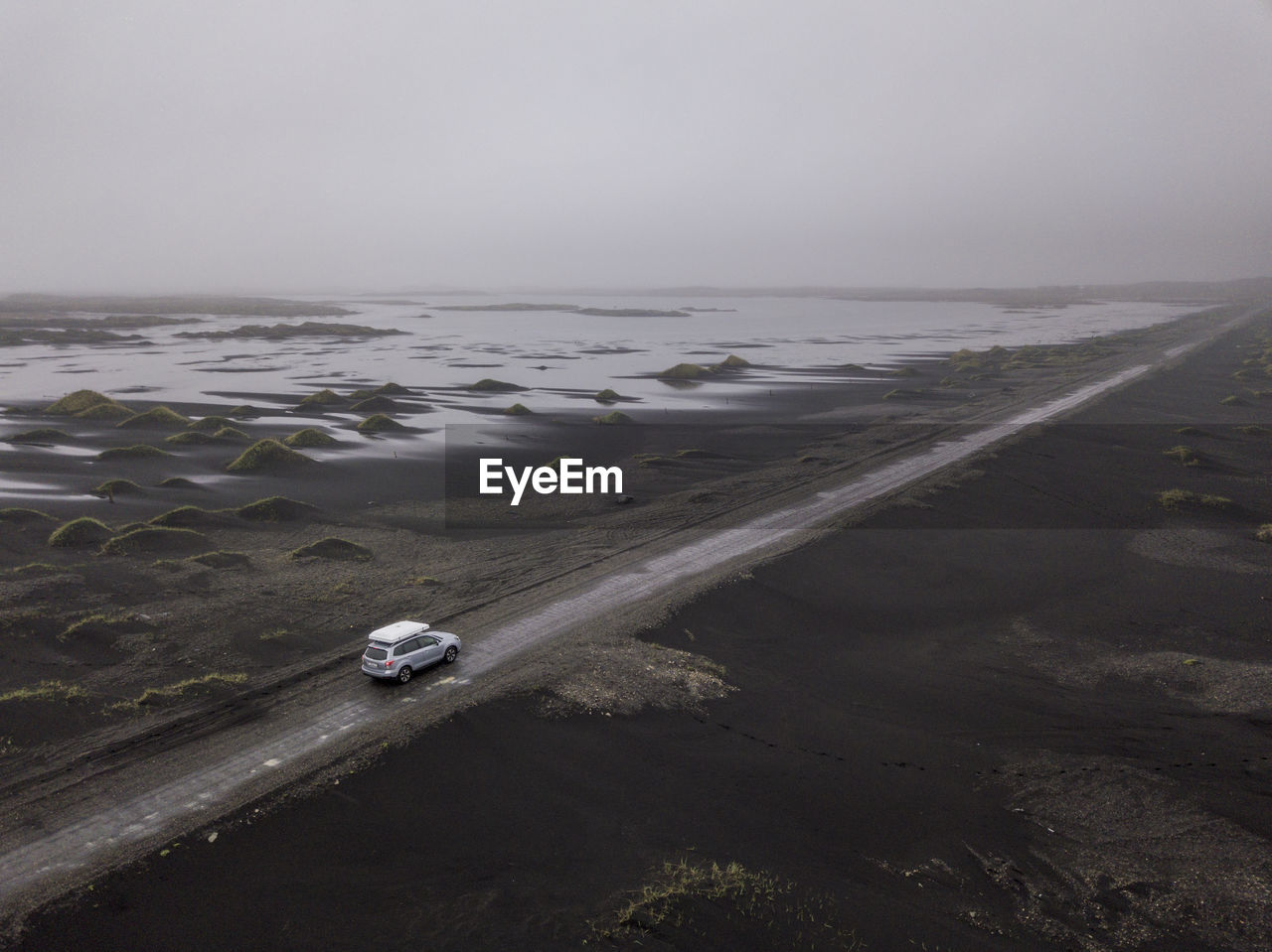 Aerial of car driving down sandy gravel road near stokksnes, ice