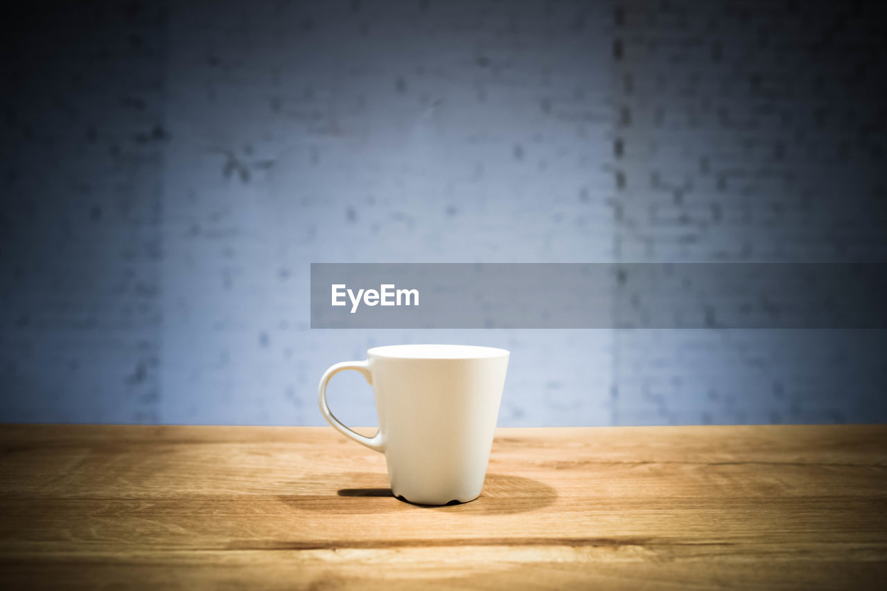 Close-up of coffee cup on table against wall