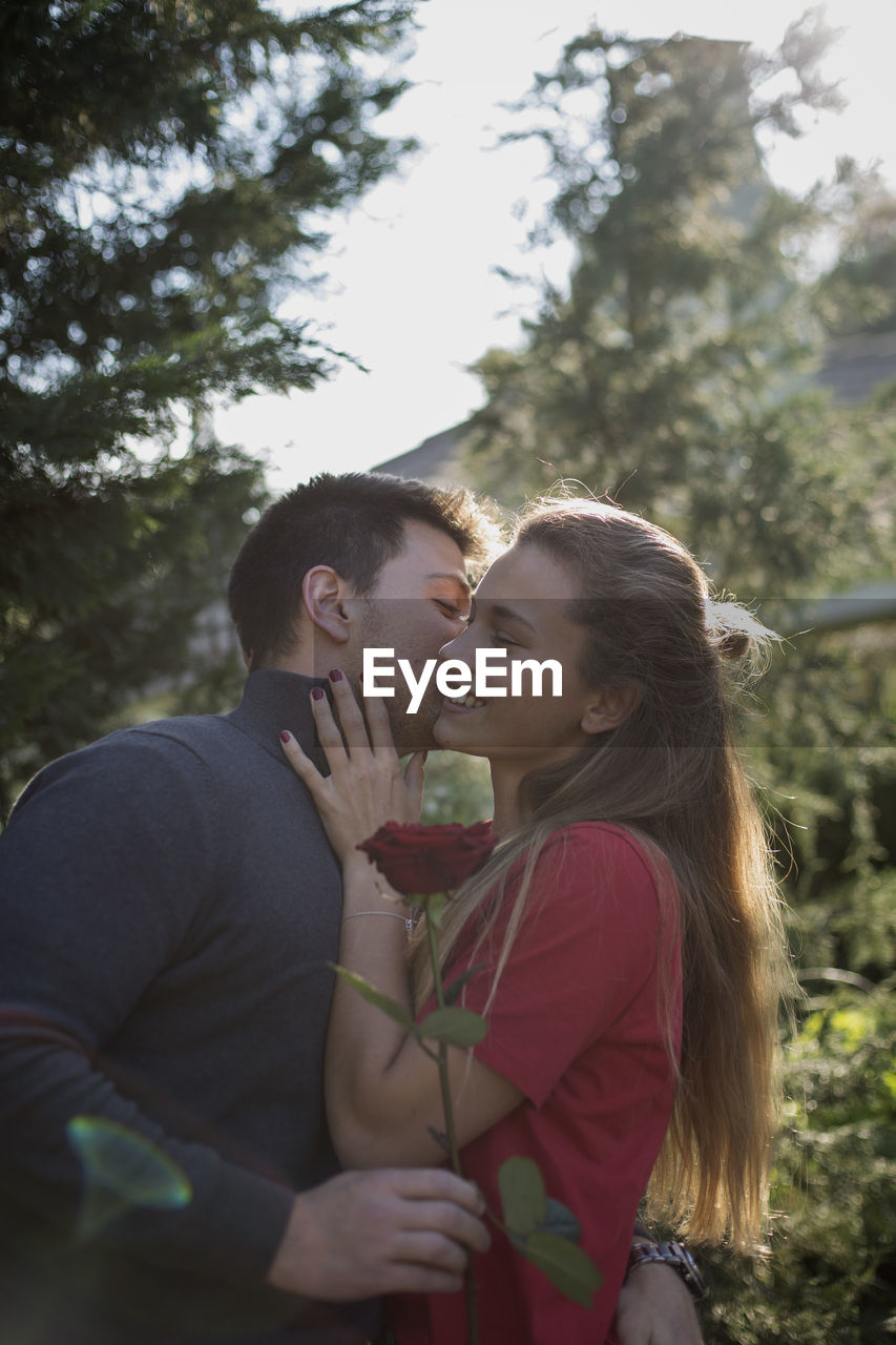 YOUNG COUPLE KISSING AGAINST PLANTS