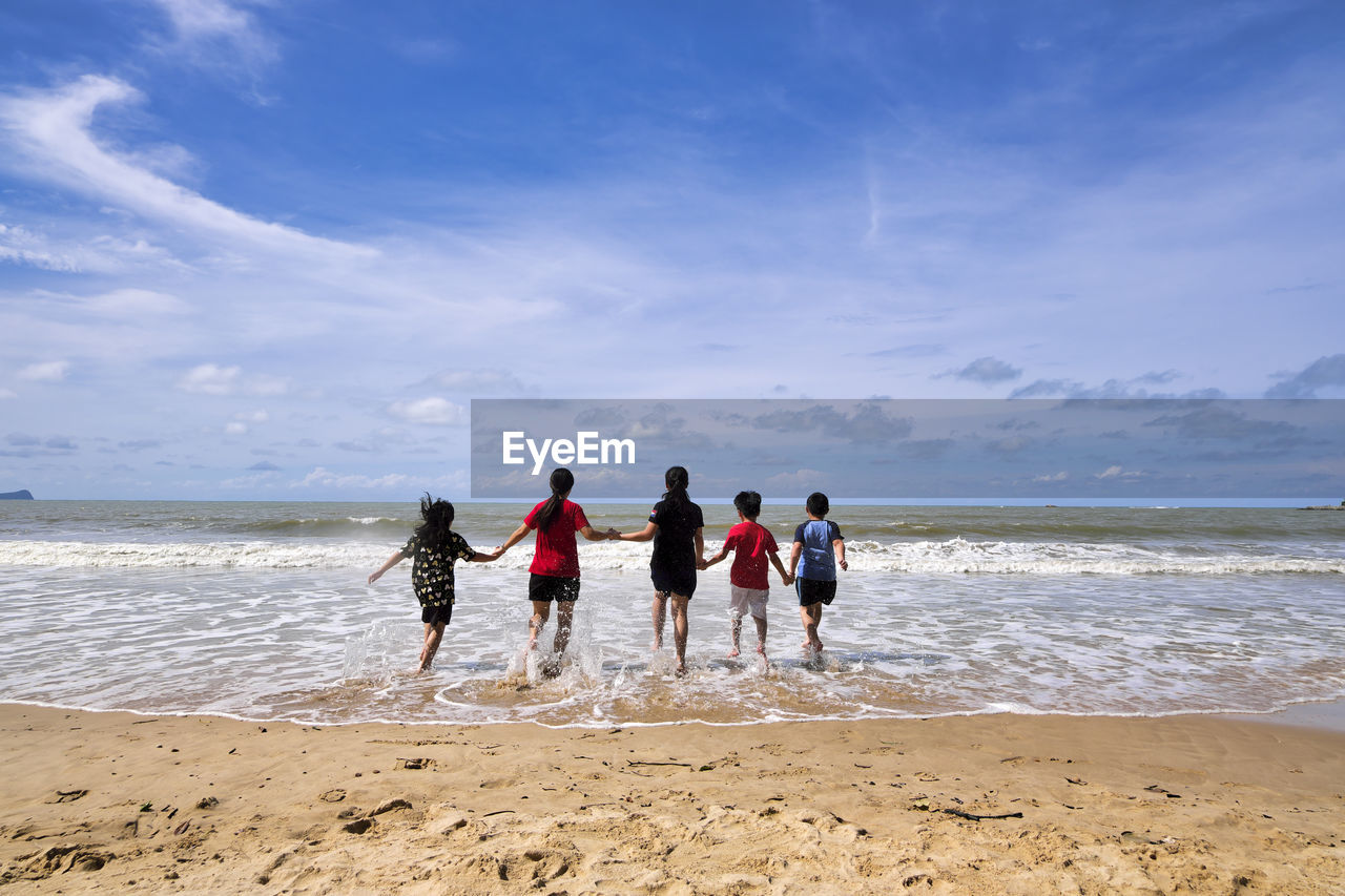 People enjoying on beach against sky