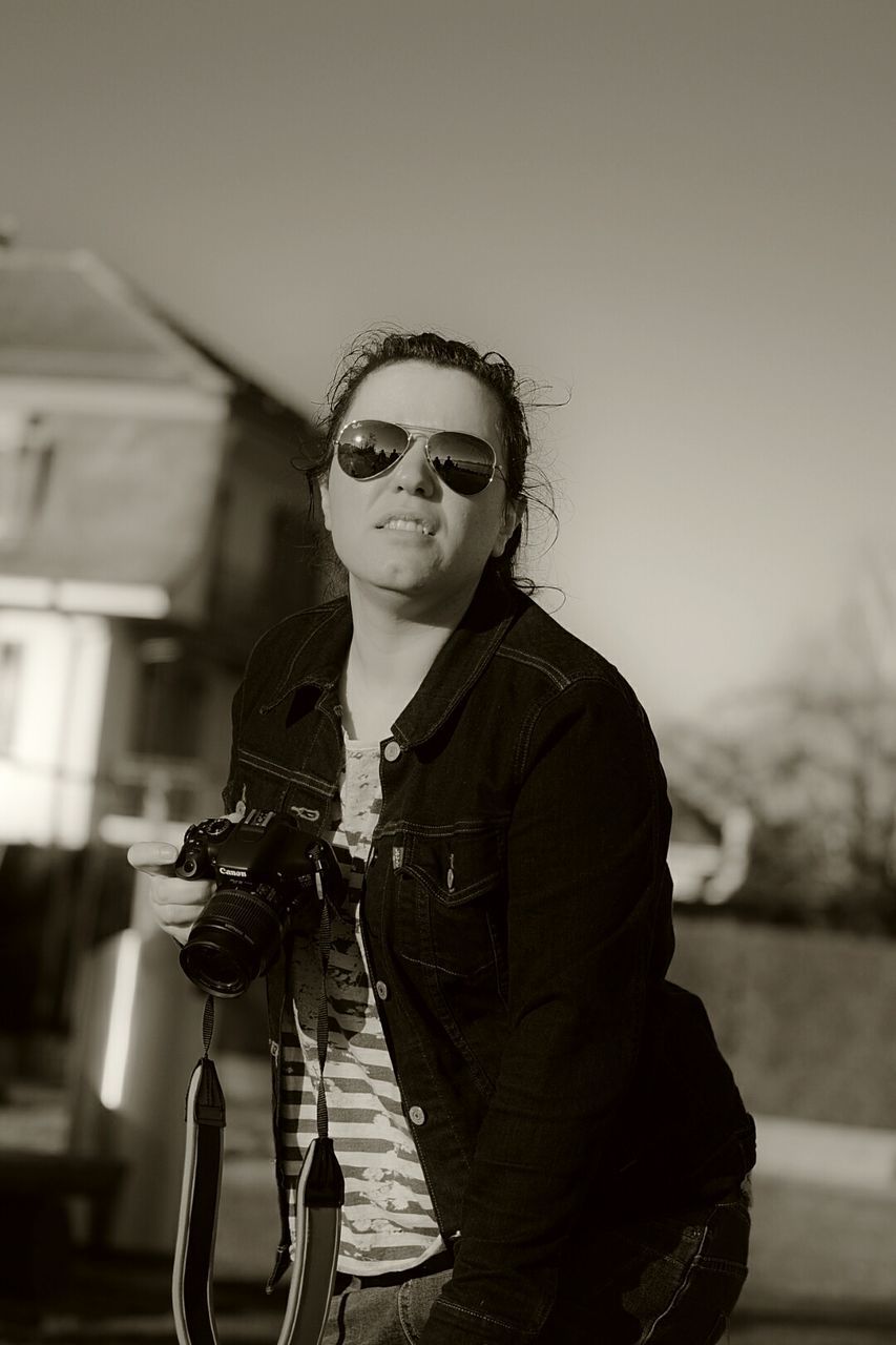 Woman with camera standing against sky