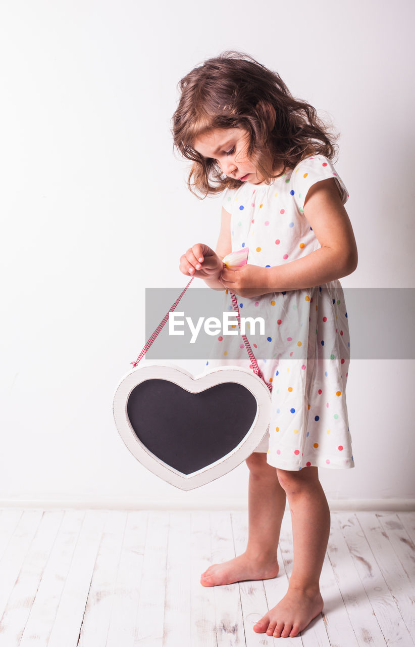 Full length of cute girl standing against wall