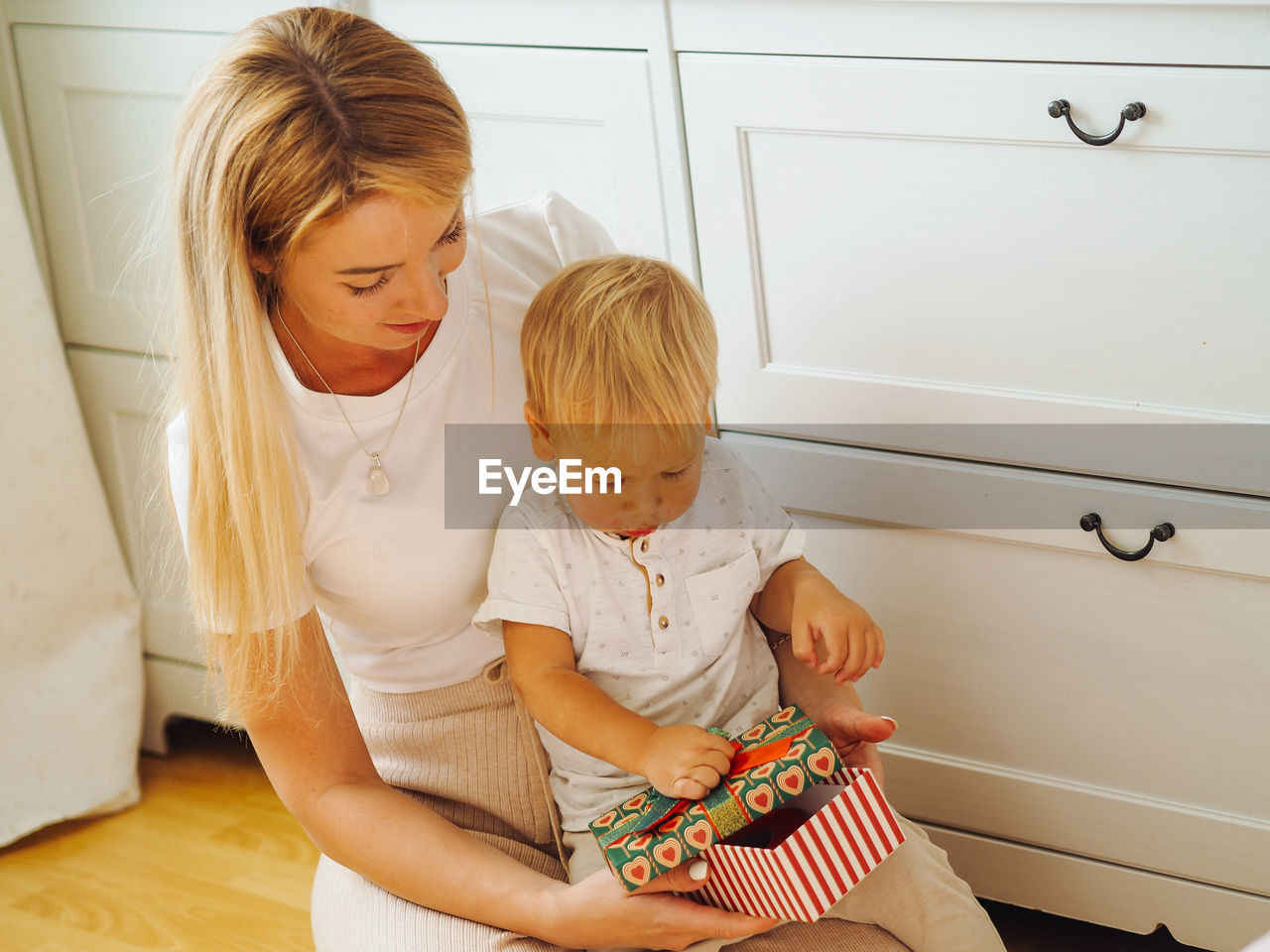 Mother and son holding box while sitting at home