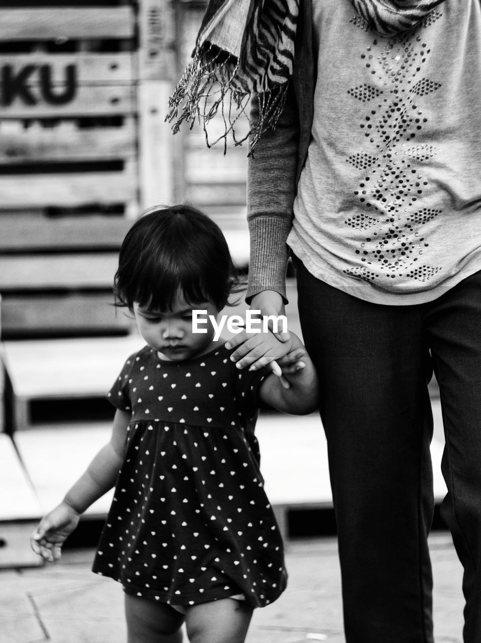 Midsection of mother holding daughter hand on footpath