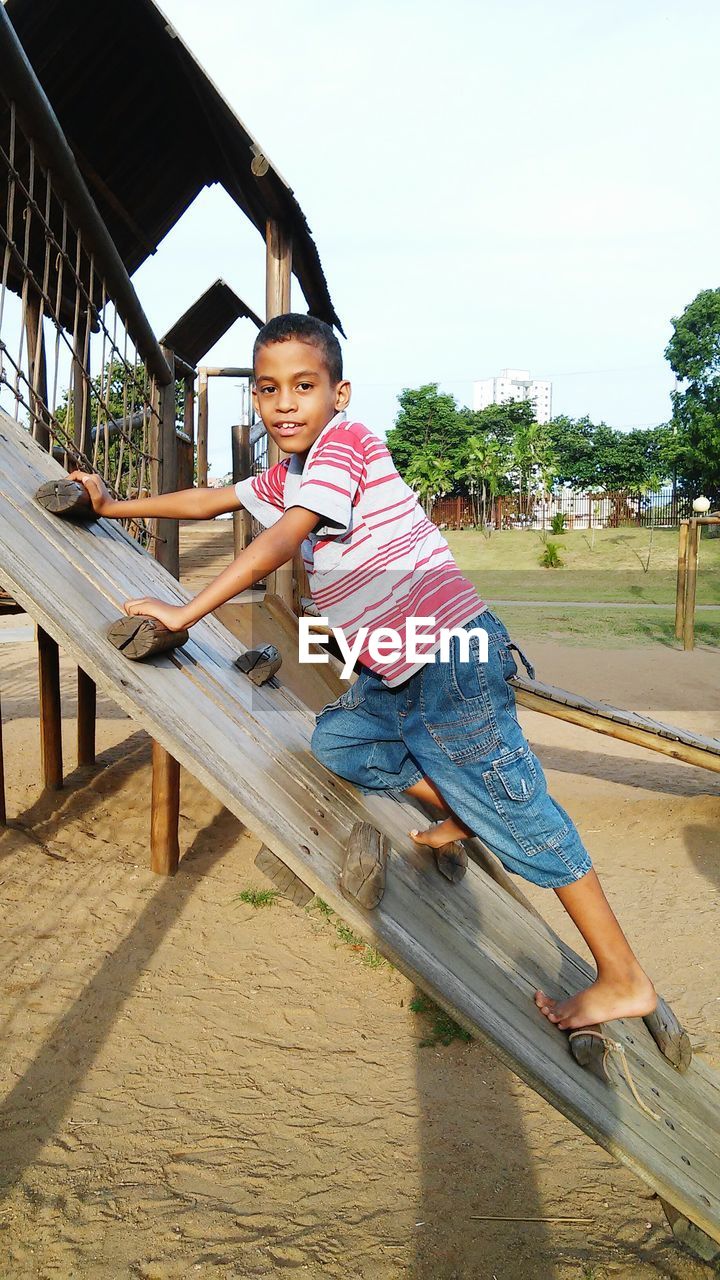 Portrait of boy playing on jungle gym at playground