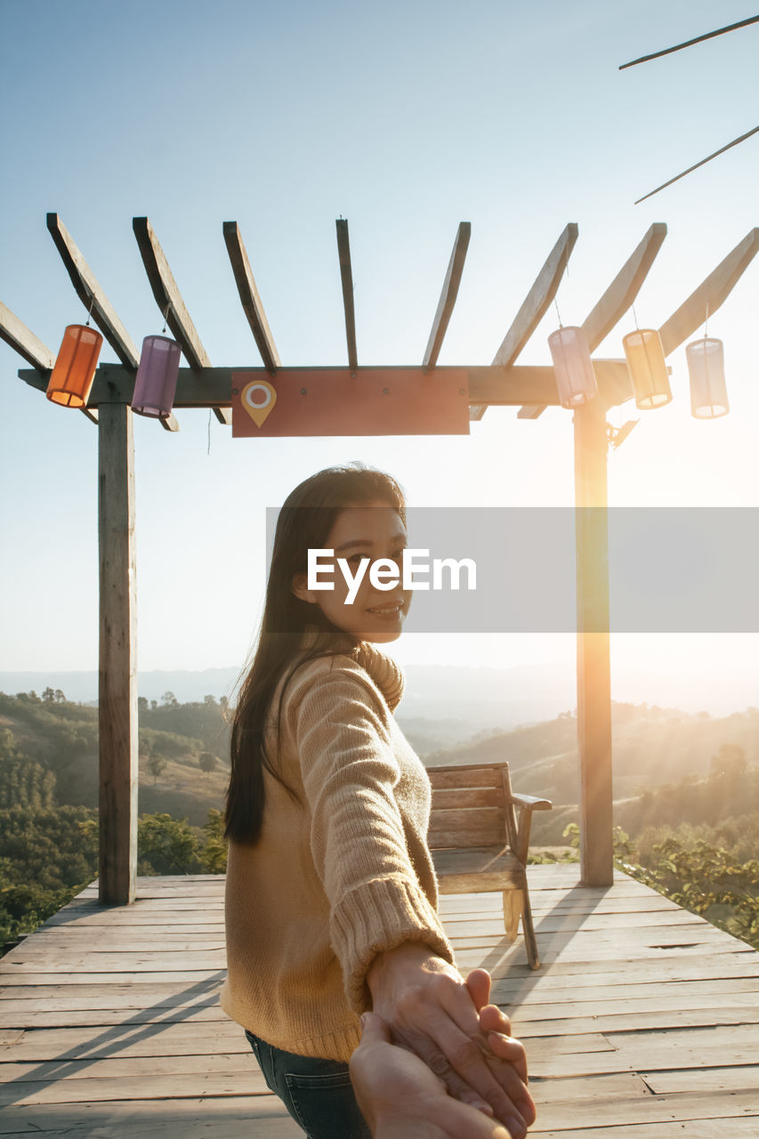 PORTRAIT OF HAPPY GIRL STANDING AGAINST WOODEN SKY