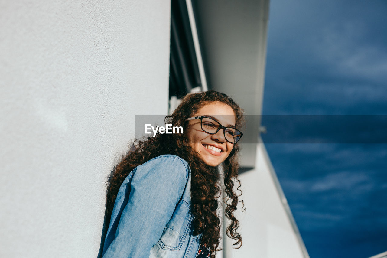 Smiling young woman against wall