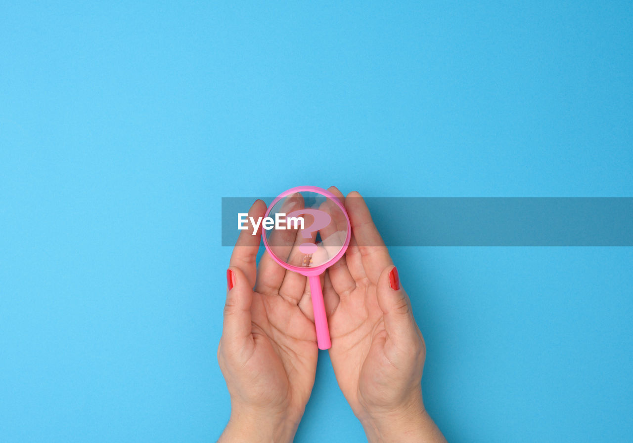 CLOSE-UP OF WOMAN HAND AGAINST BLUE WALL