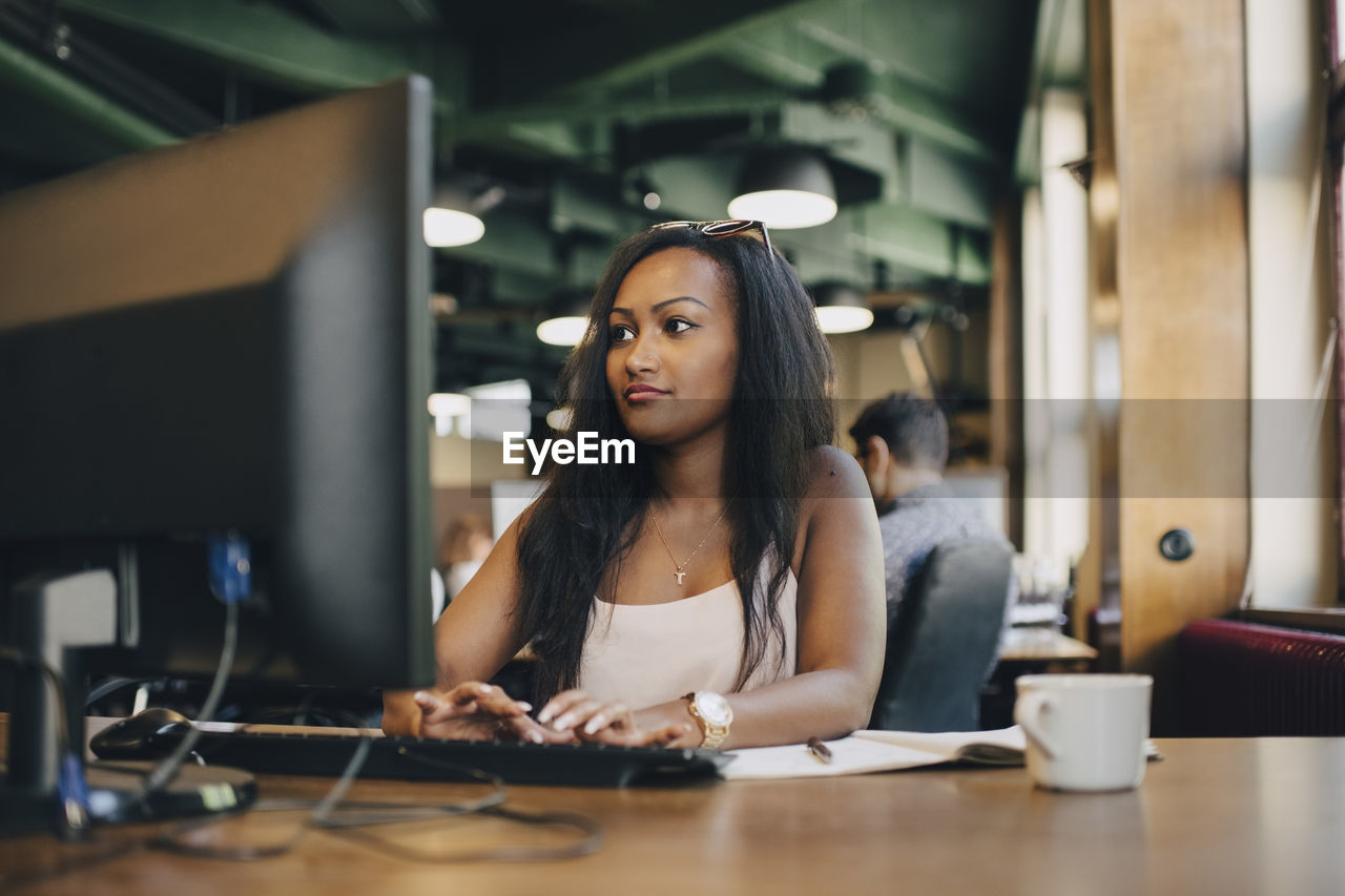 Young businesswoman using computer at desk in creative office