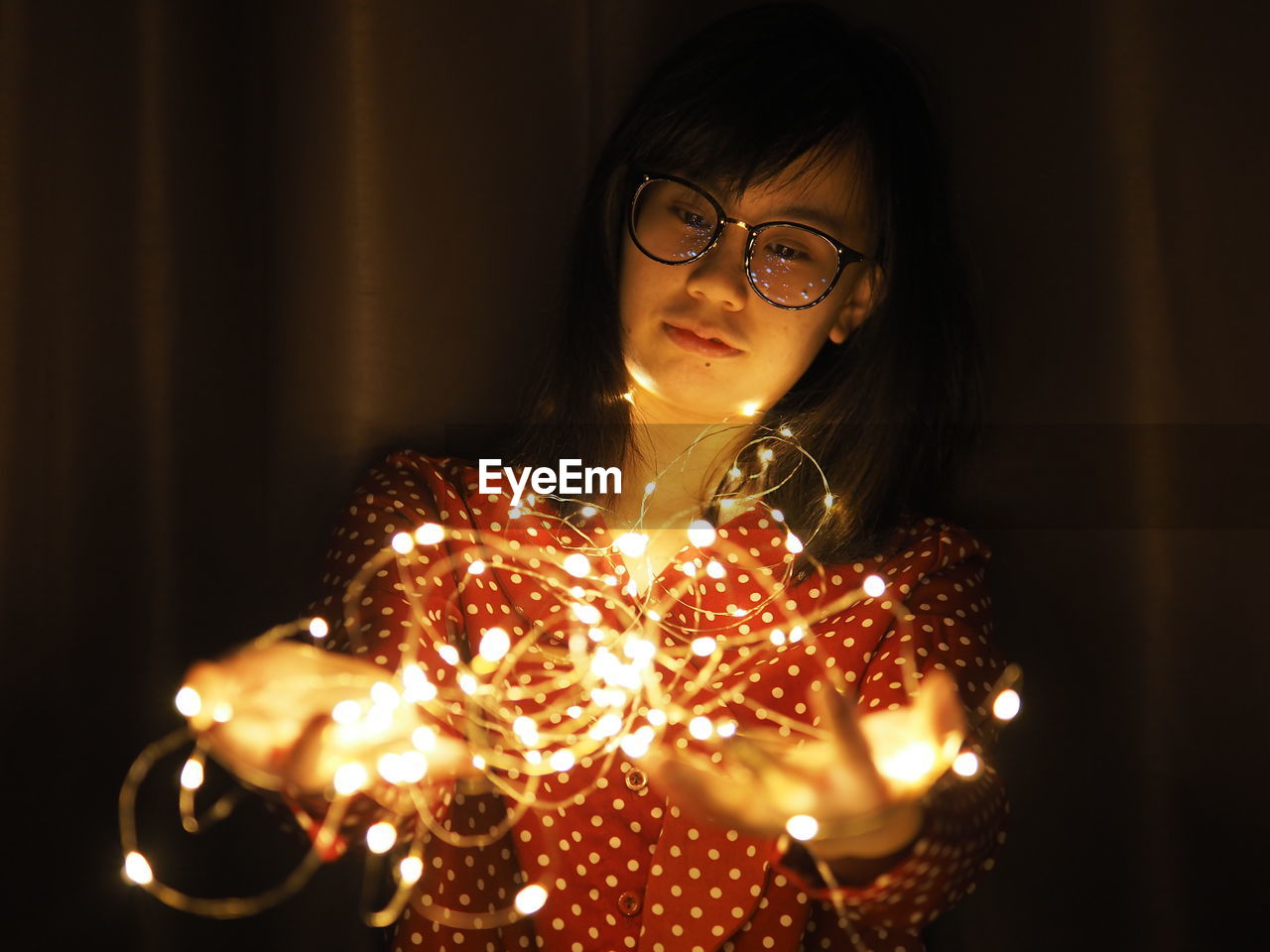 Woman holding illuminated string lights at home