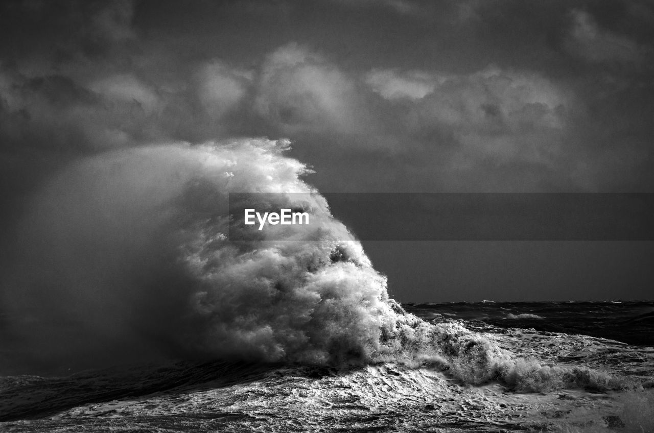 Sea waves rushing towards shore against sky