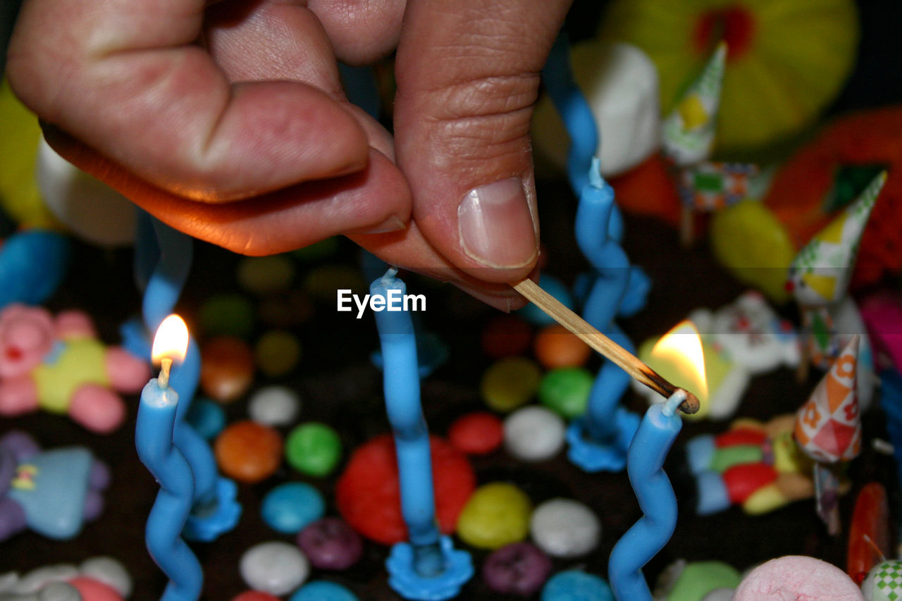 Close-up of person burning candles on cake