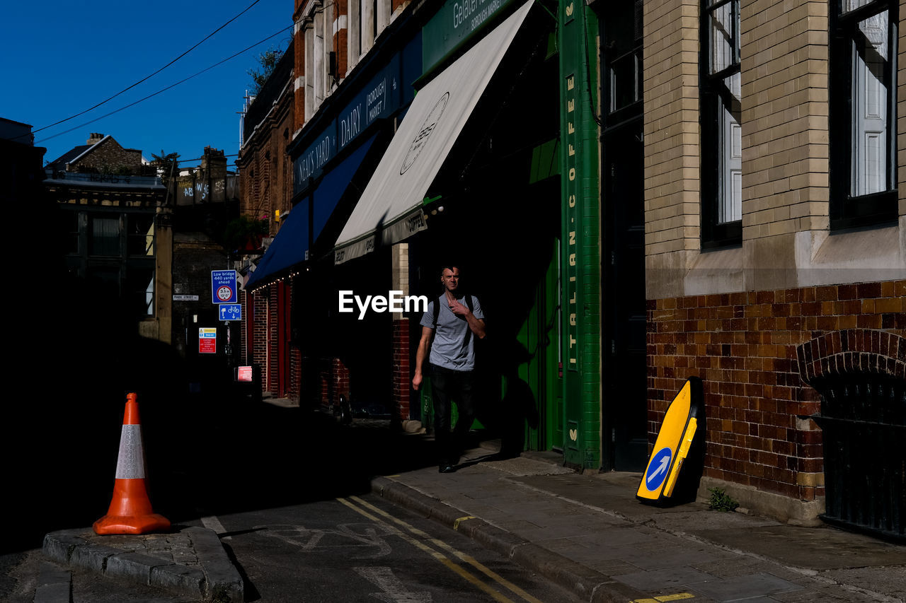 MAN STANDING ON STREET BY BUILDINGS IN CITY