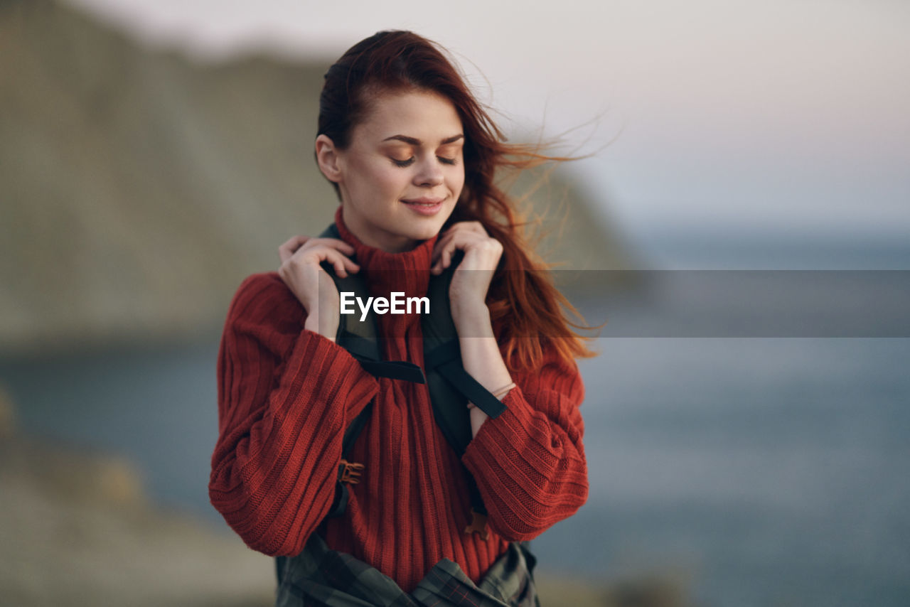 BEAUTIFUL YOUNG WOMAN STANDING AGAINST SEA