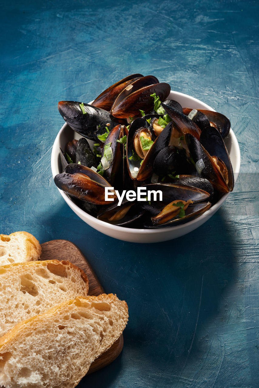 Boiled mussels in bowl with parsley and onion