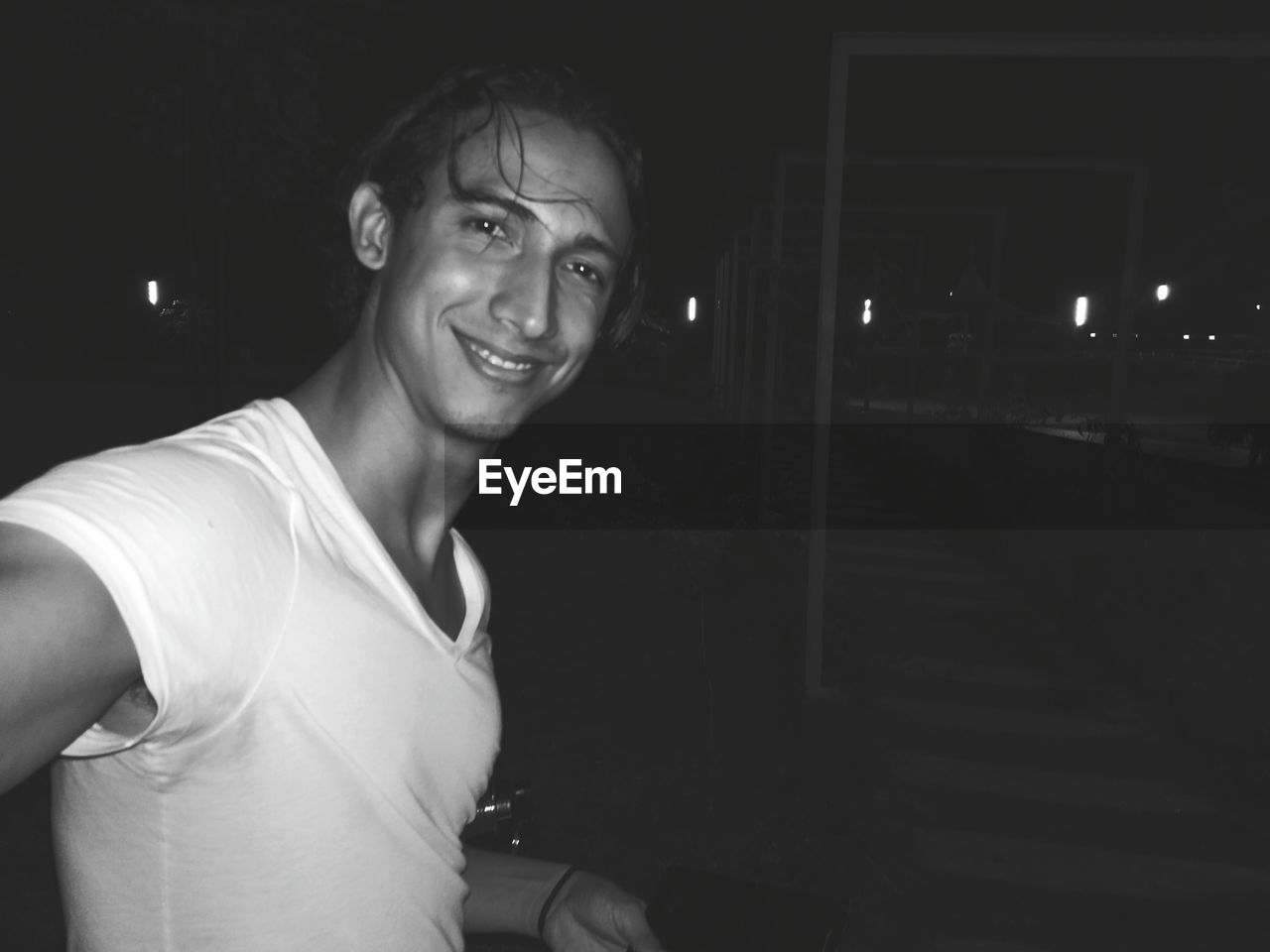 Portrait of smiling young man standing outdoors at night