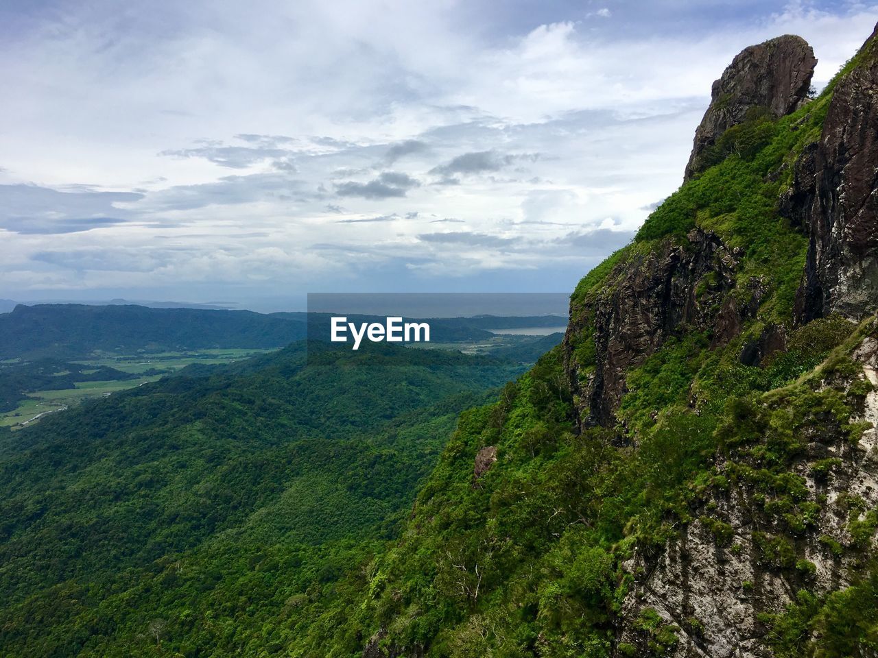 Scenic view of green mountains against cloudy sky