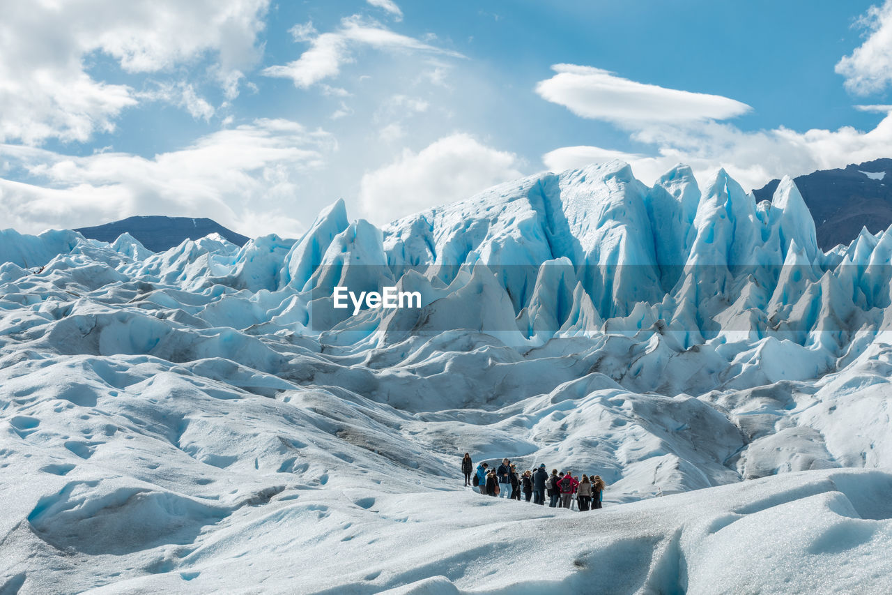 PEOPLE ON SNOWCAPPED LANDSCAPE AGAINST SKY