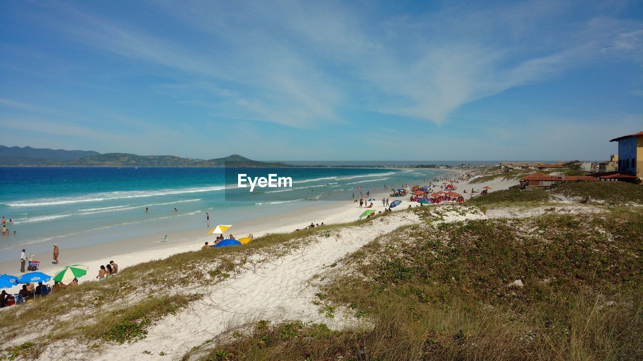 GROUP OF PEOPLE ON BEACH AGAINST SKY