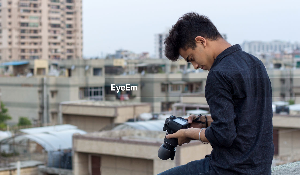 Young photographer exploring terrace while clicking photographs in his dslr camera. world pandemic.