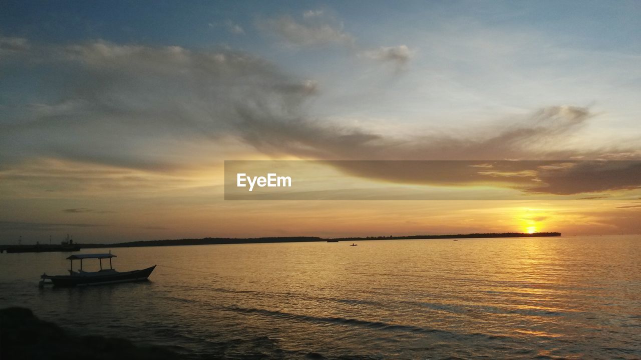 BOAT SAILING IN SEA AGAINST SKY DURING SUNSET