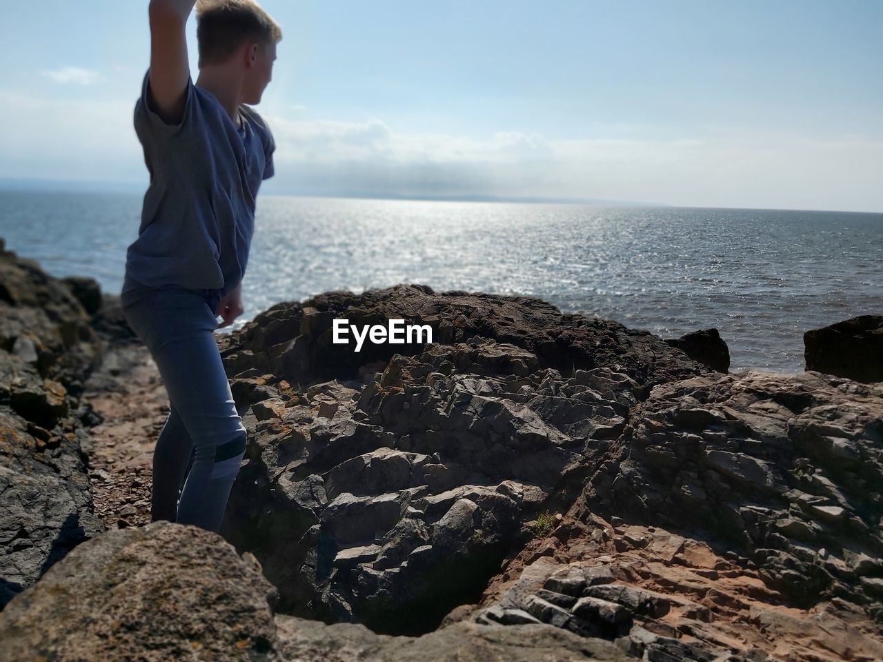 FULL LENGTH OF MAN ON ROCK AT BEACH