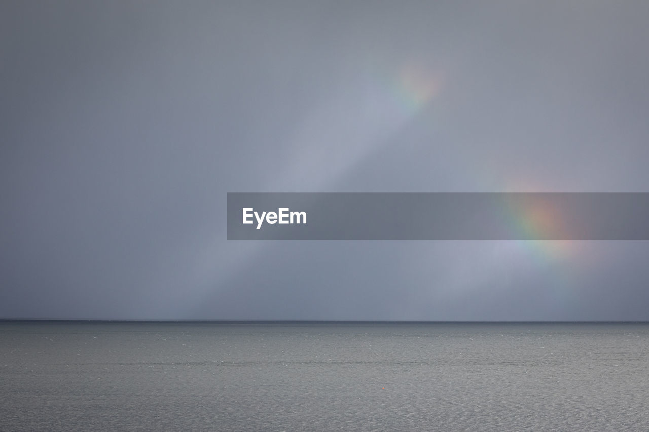 Scenic view of rainbow over sea against sky