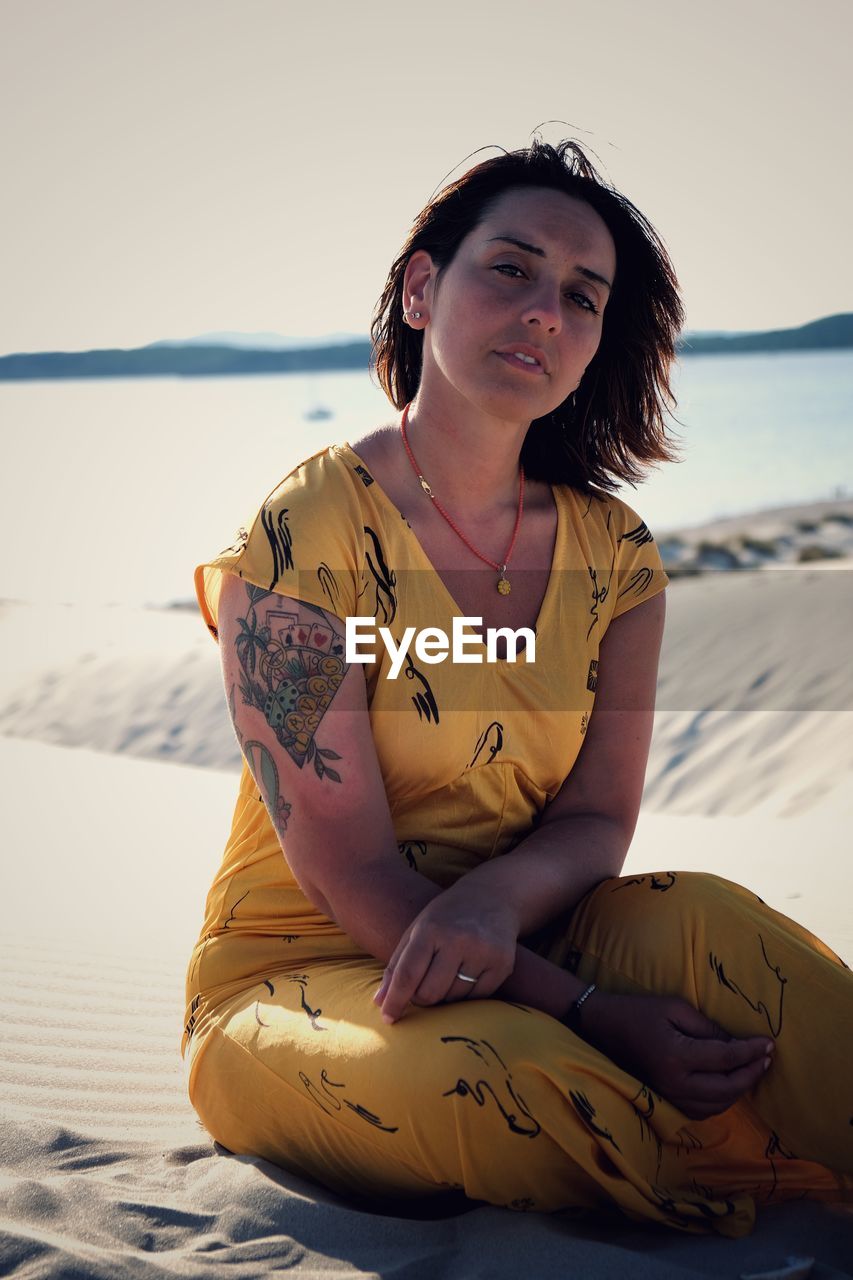 Portrait of smiling young woman sitting on beach